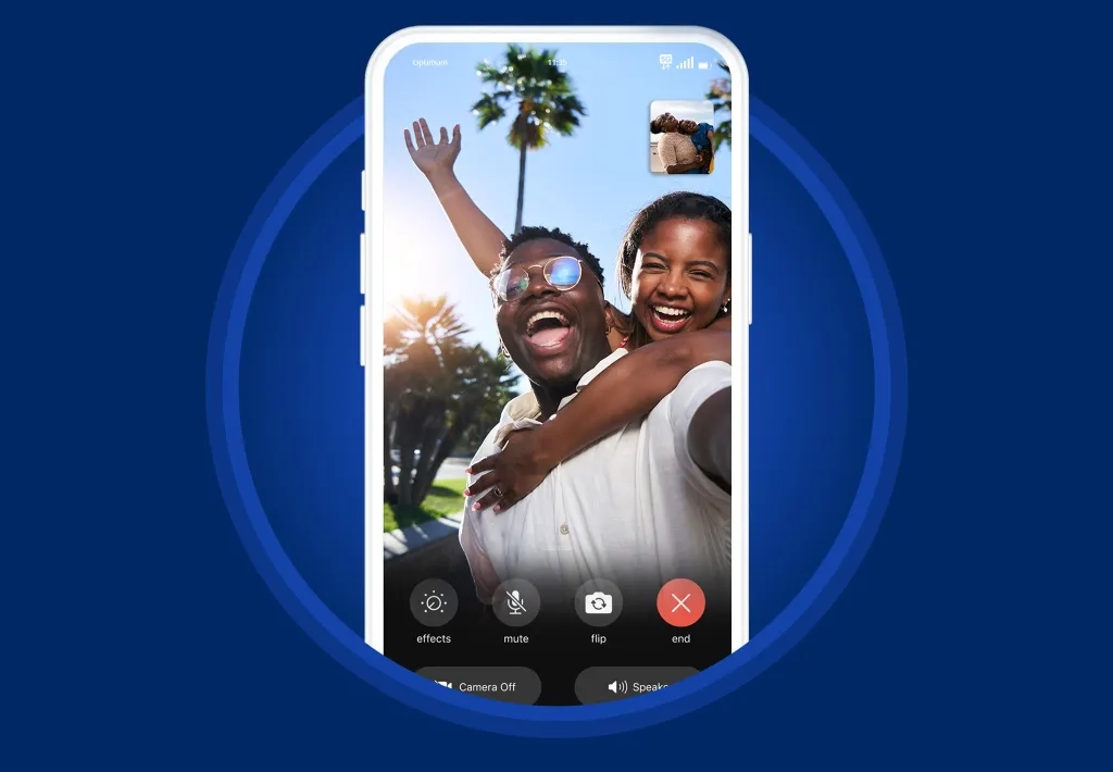 A man and woman video call in front of palm trees in the Caribbean, connecting via Optimum’s international mobile phone services.